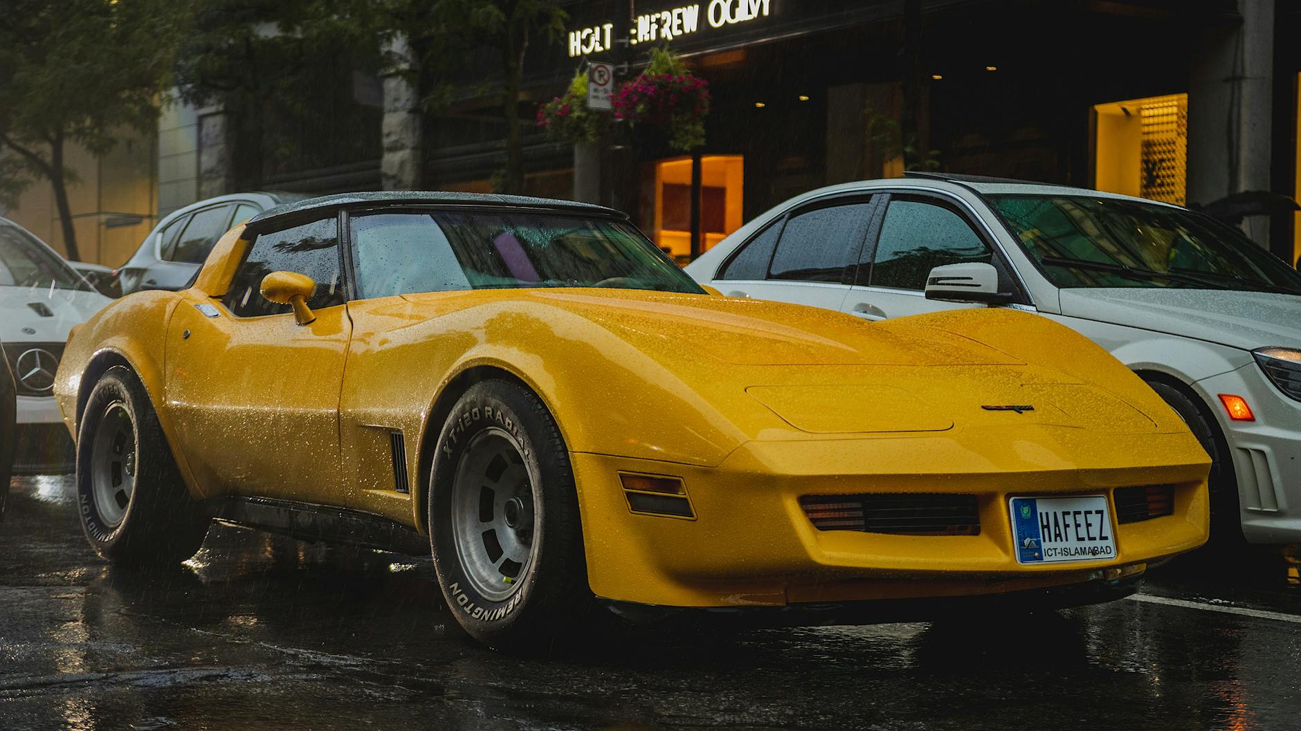 a yellow corvette parked on the street in front of a building