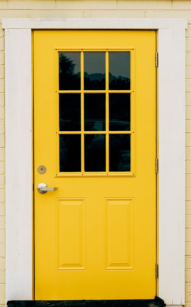 yellow wooden door with gold lever