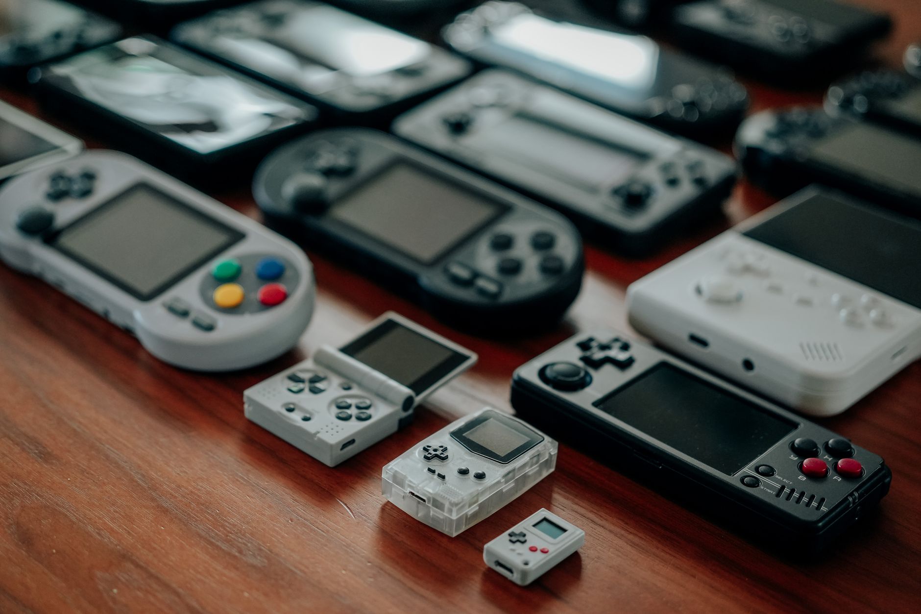 various retro portable gaming consoles on a wooden table